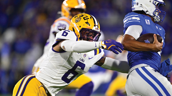 LSU defender in white jersey (#6) reaches to tackle a blue-clad opponent holding the football.