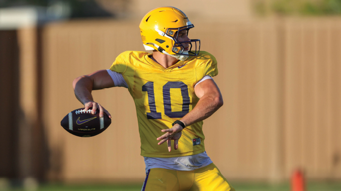 Quarterback in yellow uniform (#10) about to throw a football during practice on a grassy field.
