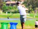 Golfer in white shirt and cap mid-swing on a sunny golf course.