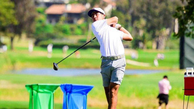 Golfer in white shirt and cap mid-swing on a sunny golf course.