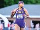 LSU track sprinter in a purple uniform and headband racing on an outdoor track, bib reads Shawnti Jackson.