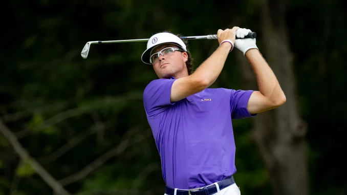 Golfer in a purple LSU polo swings a club during a backswing with a white visor and protective glasses.