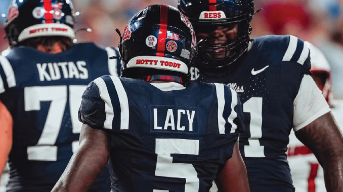 Ole Miss Rebels football players seen from the back during a game; center is LACY #5, flanked by teammates KUTAS #70 and another player #41.