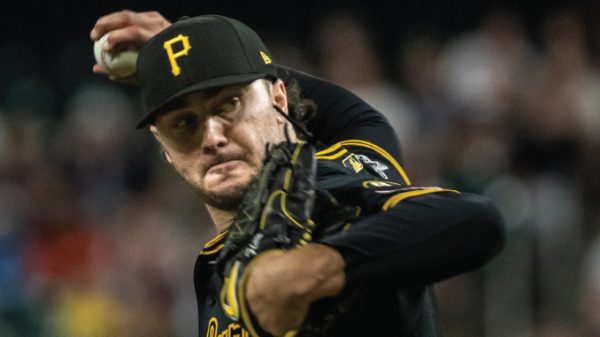 Pittsburgh Pirates pitcher mid-pitch in a black and gold uniform, throwing the ball with glove up near his face.