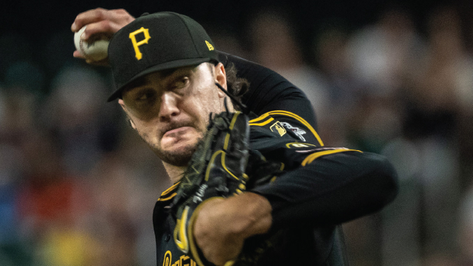 Pittsburgh Pirates pitcher mid-pitch in a black and gold uniform, throwing the ball with glove up near his face.