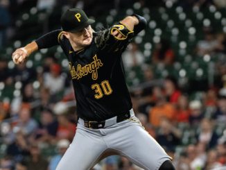 Pirates pitcher in black uniform with number 30 delivering a pitch on the mound during a game.