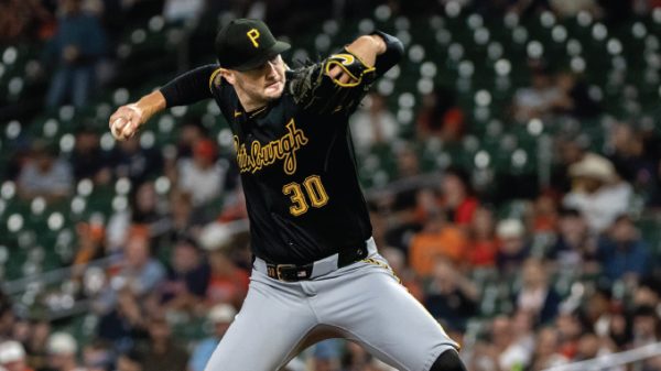 Pirates pitcher in black uniform with number 30 delivering a pitch on the mound during a game.