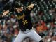 Pirates pitcher in black uniform with number 30 delivering a pitch on the mound during a game.