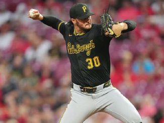 Pittsburgh Pirates pitcher in black uniform mid-pitch, wearing number 30, on the mound with a blurred crowd in the background