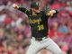 Pittsburgh Pirates pitcher in black uniform mid-pitch, wearing number 30, on the mound with a blurred crowd in the background