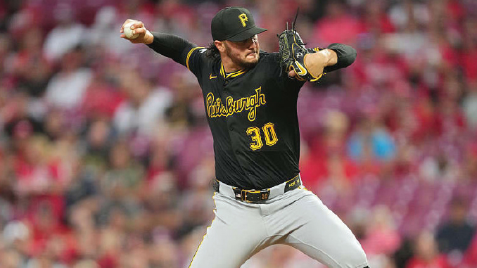 Pittsburgh Pirates pitcher in black uniform mid-pitch, wearing number 30, on the mound with a blurred crowd in the background