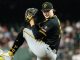 Baseball pitcher in a Pittsburgh Pirates uniform mid-pitch on the mound, wearing black jersey with yellow trim, gray pants, and a black cap.