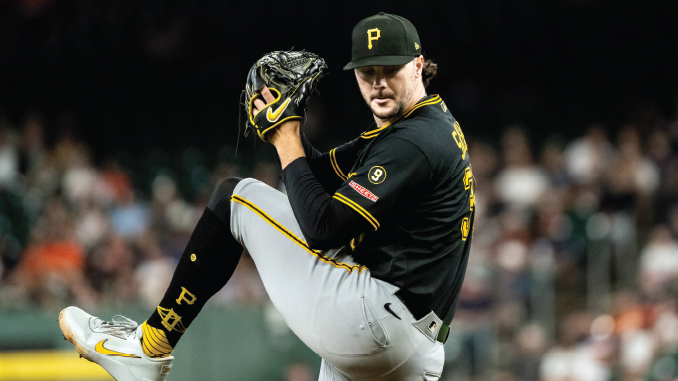 Baseball pitcher in a Pittsburgh Pirates uniform mid-pitch on the mound, wearing black jersey with yellow trim, gray pants, and a black cap.