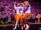 LSU football players in white and gold celebrate a touchdown in the end zone as the crowd cheers nearby Camerawork captures the moment.