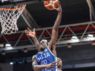 Basketball player in a blue jersey (number 20) jumping to dunk the ball through the hoop during a game.