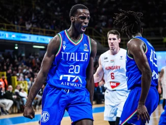Italy basketball players in blue jerseys celebrate on court during a game, one shouting with fist clenched.