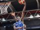 Basketball player in a blue jersey (number 20) jumping to dunk the ball through the hoop during a game.