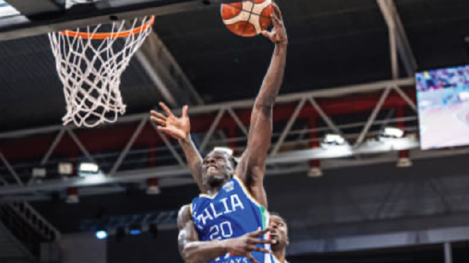 Basketball player in a blue jersey (number 20) jumping to dunk the ball through the hoop during a game.