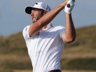 Male golfer in a white polo shirt and cap mid-swing on a golf course, follow-through with a raised club.