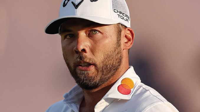 Close-up of a golfer wearing a white polo with Mastercard logo on the collar and a white cap, looking focused.