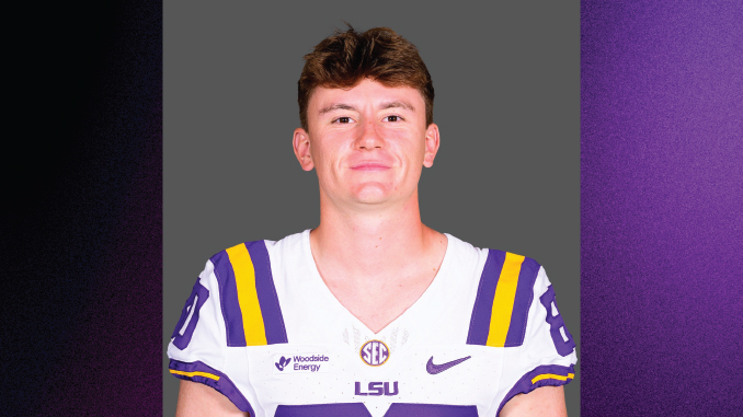 Portrait of a LSU football player in a white jersey with purple and gold stripes, standing against a gray backdrop