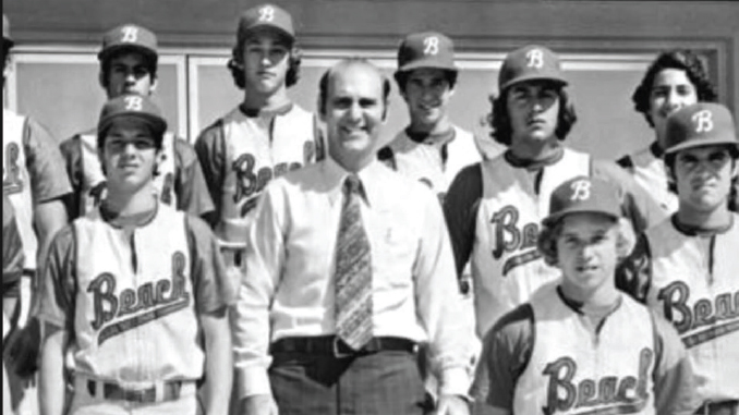 Black-and-white photo of a baseball team posing with their coach in a shirt and tie; players wear matching uniforms with B logos.