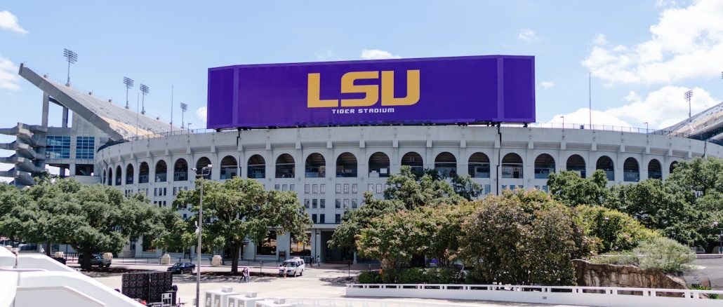 Exterior of LSU Tiger Stadium with a large purple LSU billboard on the façade on a sunny day