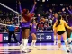 LSU women's volleyball players in purple celebrate a point on the court as fans cheer in the stands behind them.