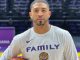 Basketball player in a gym holding a basketball, wearing a gray shirt that says 'FAMILY' with a tiger logo beneath it.