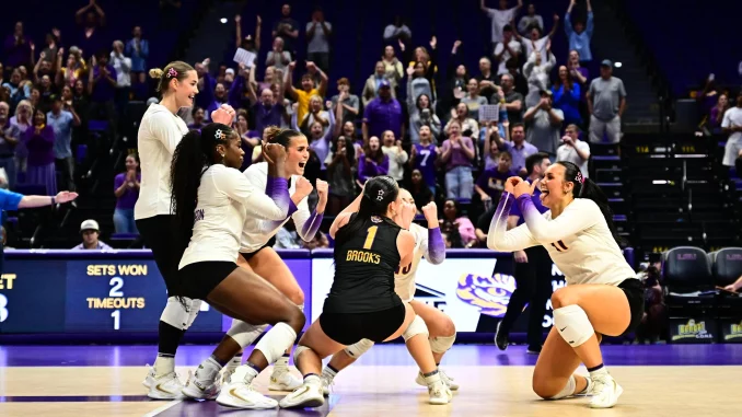 LSU women's basketball players celebrate on the court as fans cheer in the stands.