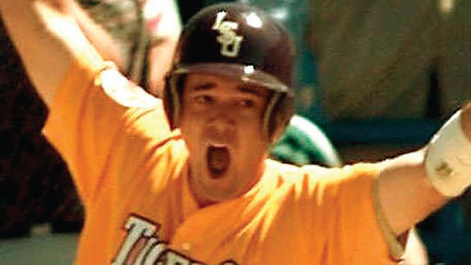 Baseball player in an orange jersey and helmet, arms raised in celebration with an open-mouthed shout.