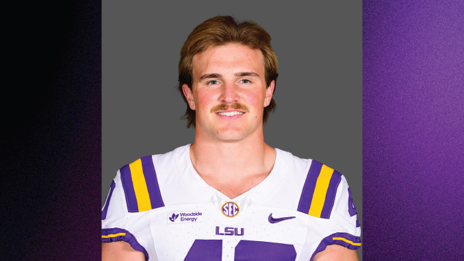 Portrait of a man in an LSU football uniform (white jersey with purple and gold stripes) against a gray background.