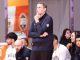 Coach stands with hand on chin while seated players watch during a timeout on the bench.